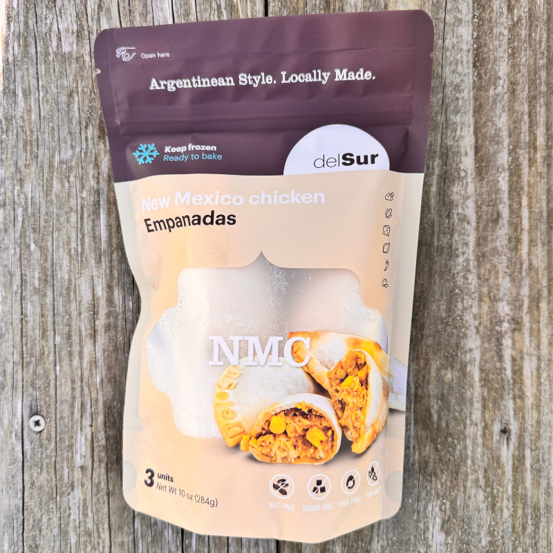 Packaged New Mexico chicken empanadas on a wooden surface