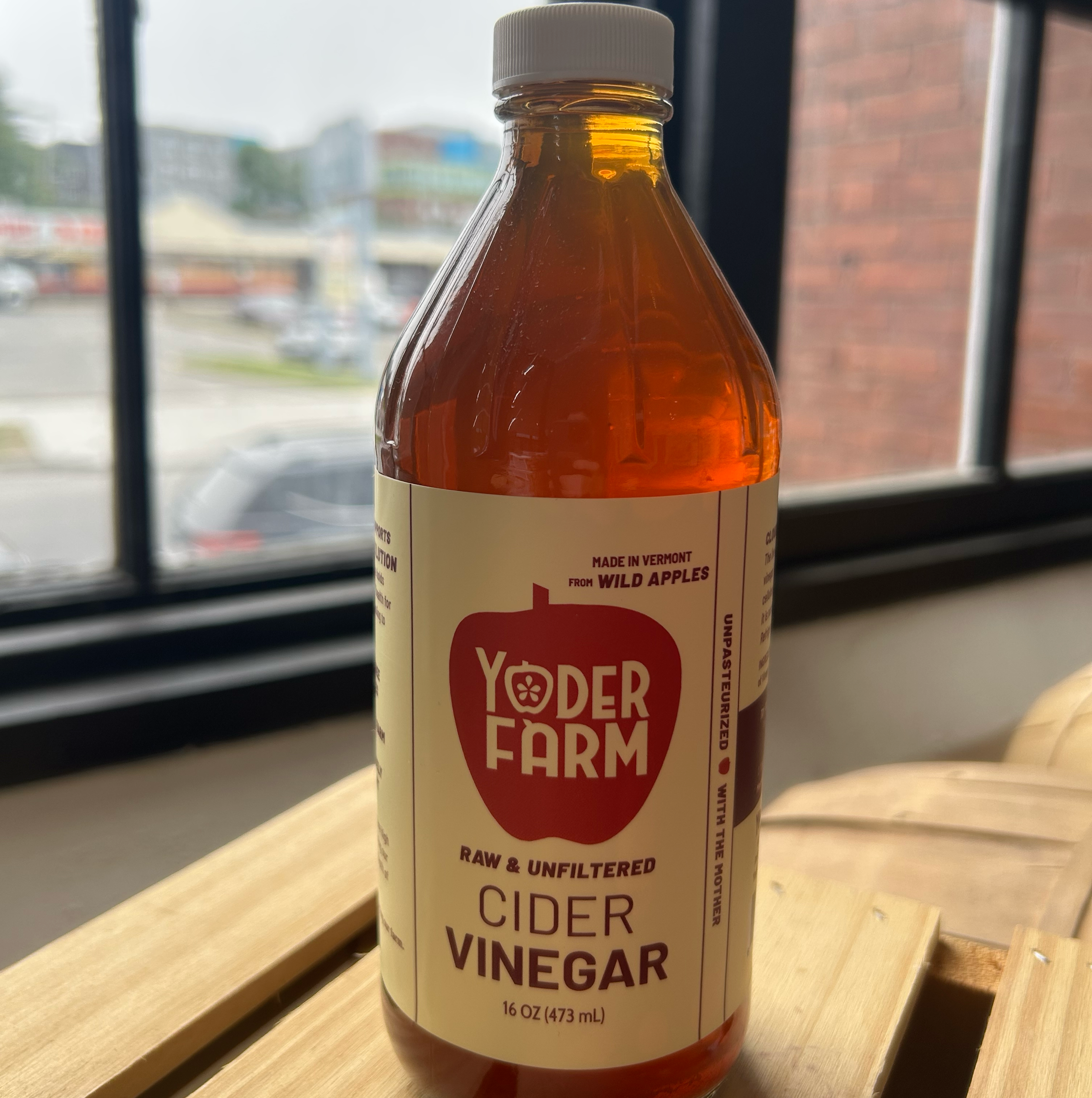 Bottle of Yoder Farm cider vinegar on a wooden surface with a window in the background