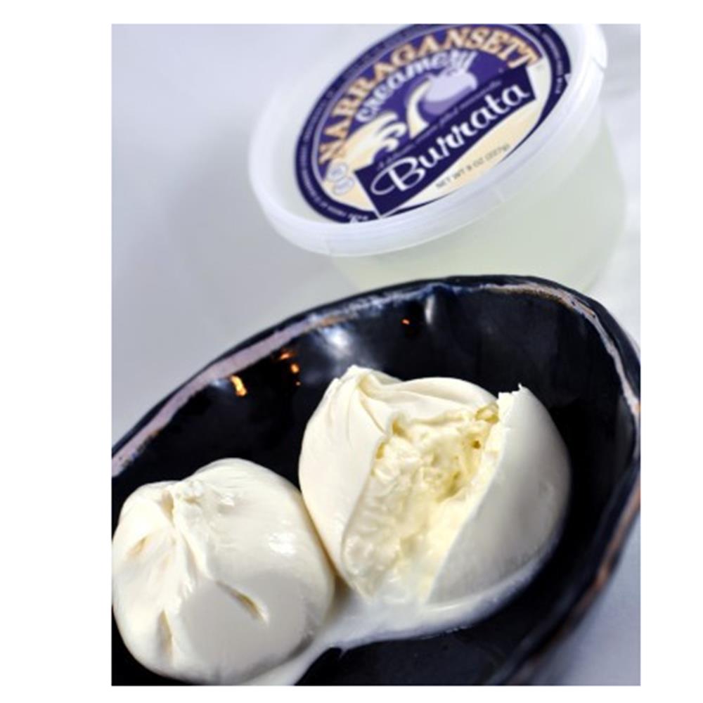 Two pieces of Buccellata cheese on a black dish with a container labeled 'Braganza' in the background.