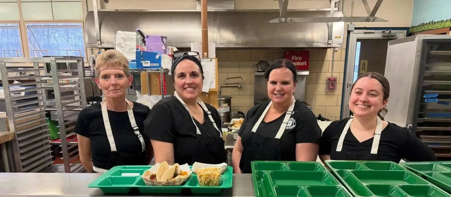 4 women pictured at Coastal Foodshed, lunch trays in foreground