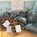 Seed starting supplies including bags of soil and seed trays on a wooden table.